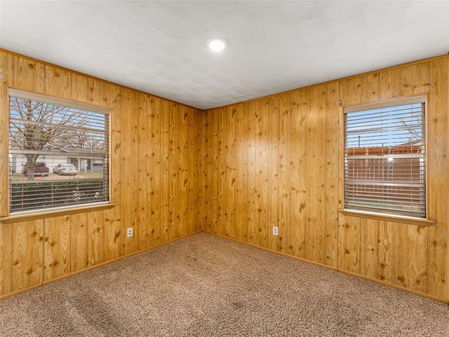 Unfurnished room featuring wooden walls, carpet floors, and a wealth of natural light | Image 26