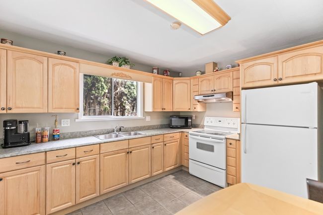 Kitchen with white appliances, light brown cabinets, and under cabinet range hood | Image 32