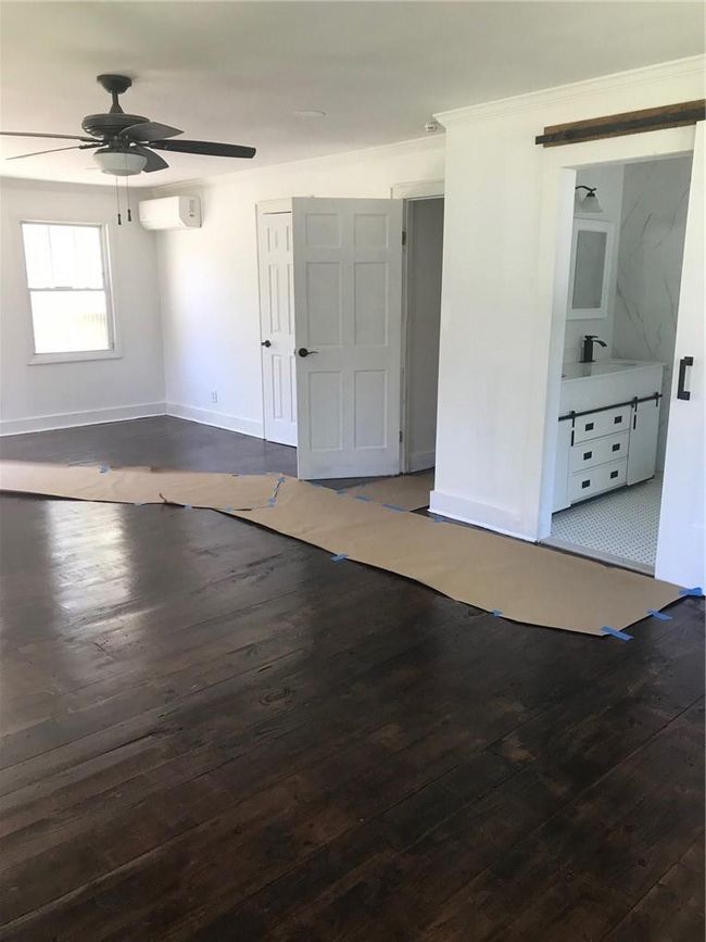 Empty room featuring dark wood-type flooring, ceiling fan, a wall unit AC, and sink | Image 21