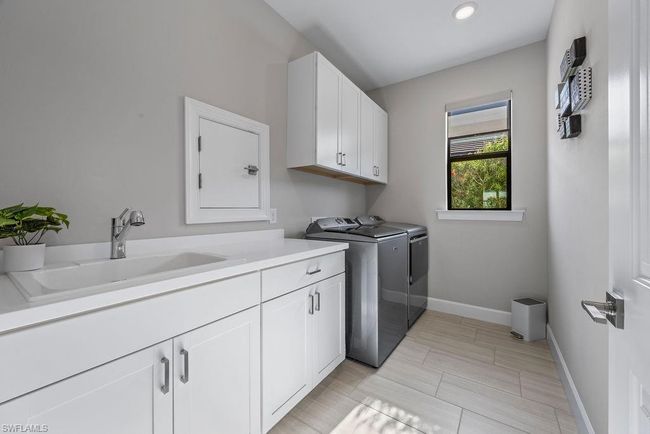 Laundry room with washing machine and clothes dryer, cabinet space, baseboards, and a sink | Image 17