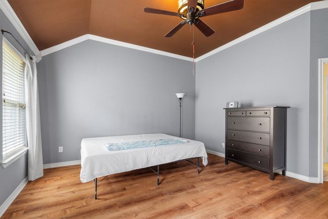 Bedroom featuring vaulted ceiling, wood finished floors, crown molding, and ceiling fan | Image 24