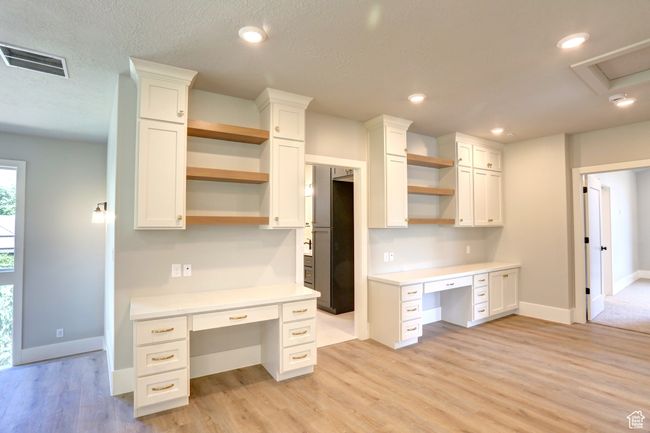 Kitchen with open shelves, built in desk, white cabinetry, light countertops, and recessed lighting | Image 19