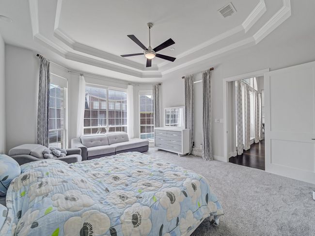 Carpeted bedroom with a raised ceiling, ornamental molding, ceiling fan, and baseboards | Image 11