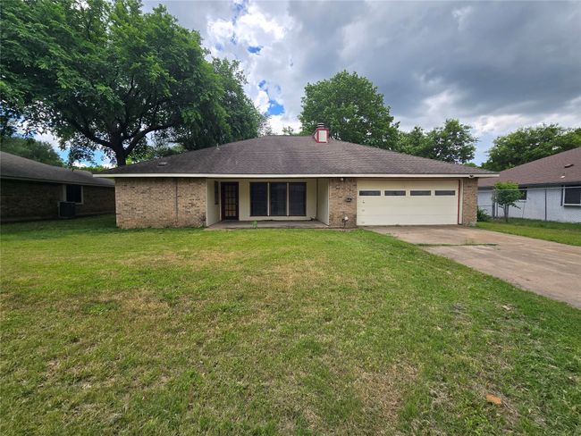 Ranch-style house featuring an attached garage, driveway, brick siding, and a chimney | Image 21