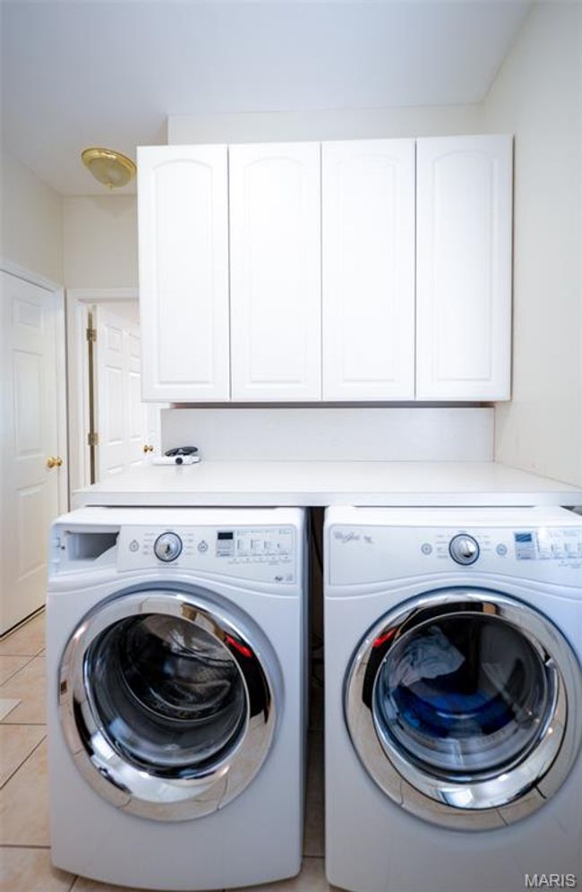 Laundry area with washing machine and dryer, cabinet space, and light tile patterned floors | Image 20