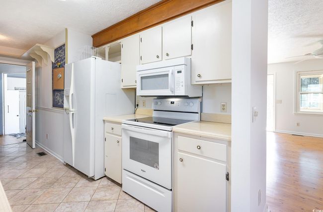 Kitchen featuring white appliances, ceiling fan, light hardwood / wood-style floors, a textured ceiling, and white cabinets | Image 5