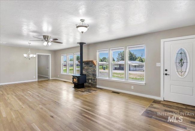 Foyer entrance with a wood stove, wood finished floors, a chandelier, a ceiling fan, and a textured ceiling | Image 22