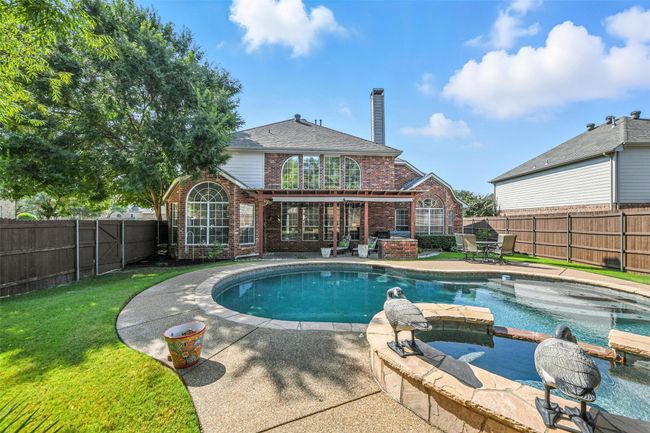 Rear view of property with brick siding, a chimney, a fenced backyard, and a patio | Image 34
