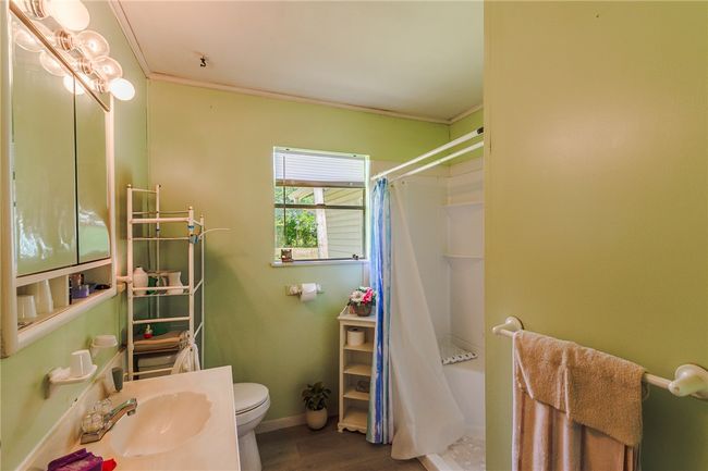 Full bath with a shower with shower curtain, wood finished floors, and crown molding | Image 24