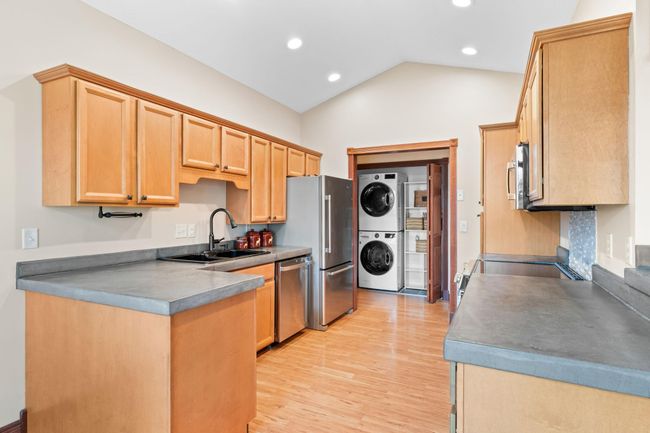 Vaulted kitchen with concrete countertops, brand new GE stainless appliances (microwave, dishwasher, and electric flat top stove), fridge 2022. | Image 13