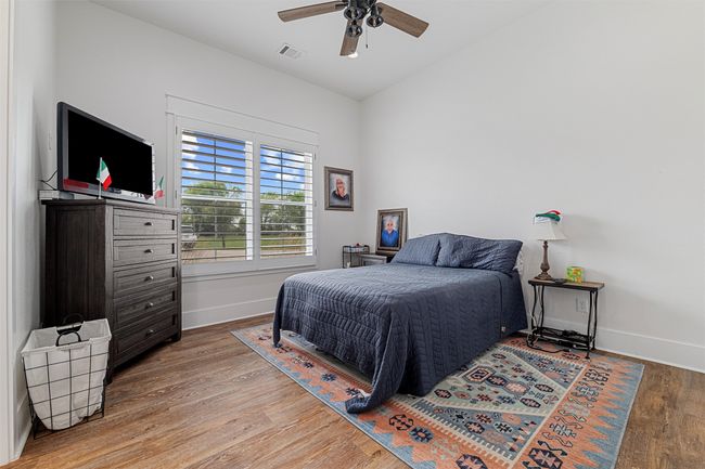 Bedroom featuring baseboards, ceiling fan, visible vents, and wood finished floors | Image 7