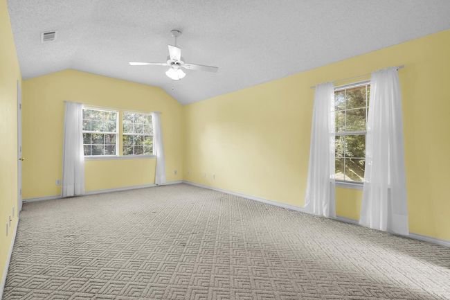 Carpeted spare room with a ceiling fan, vaulted ceiling, plenty of natural light, and a textured ceiling | Image 13