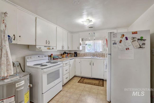 Kitchen featuring white appliances, under cabinet range hood, light countertops, and white cabinets | Image 12