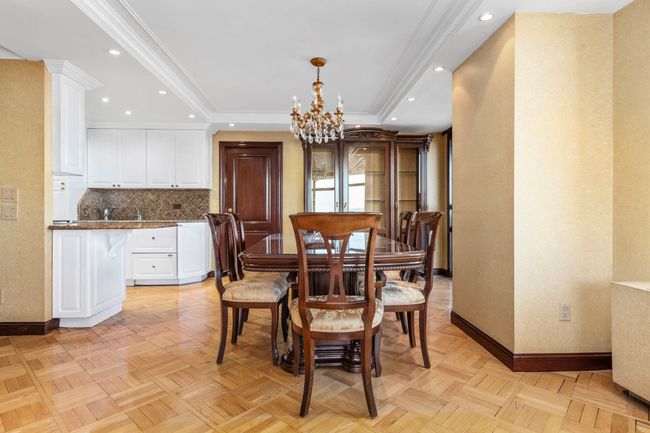 Dining space featuring a chandelier, a raised ceiling, crown molding, recessed lighting, and ornate columns | Image 7