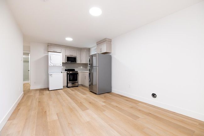 Kitchen with stacked washer / drying machine, appliances with stainless steel finishes, light wood-style flooring, light countertops, and recessed lighting | Image 38