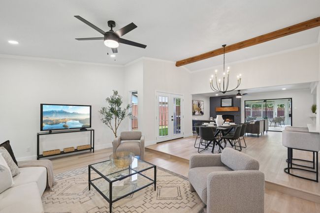 Living room with light wood-type flooring, a brick fireplace, ceiling fan, a chandelier, and recessed lighting | Image 13