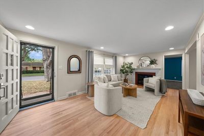 Living room featuring a healthy amount of sunlight, light refinished hardwood flooring, and a fireplace. | Image 3