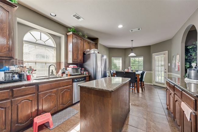 Kitchen featuring appliances with stainless steel finishes, a center island, recessed lighting, hanging light fixtures, and dark stone countertops | Image 10