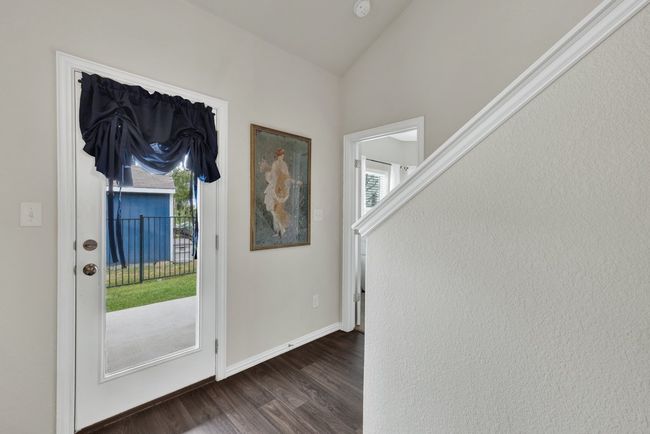 Doorway with dark wood-type flooring, baseboards, and vaulted ceiling | Image 23