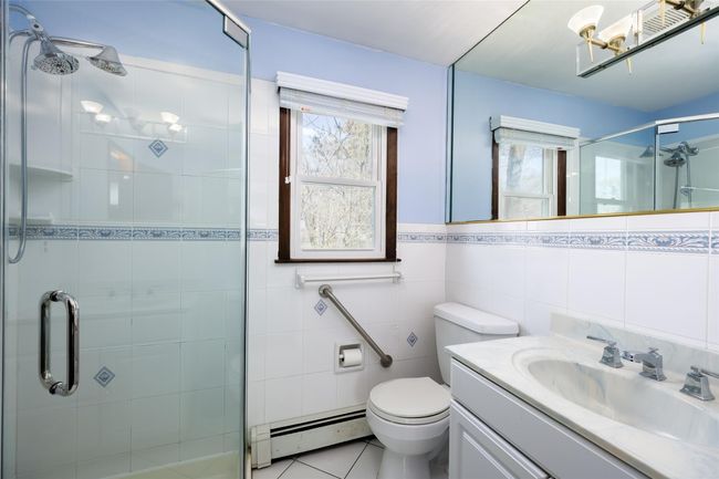 Bathroom with tile patterned flooring, a stall shower, tile walls, and a baseboard radiator | Image 29