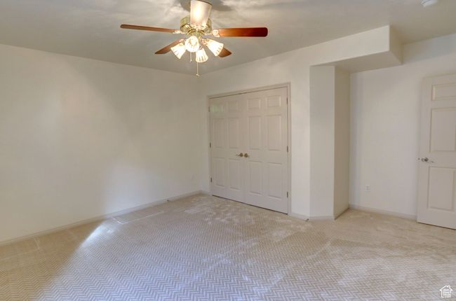 Unfurnished bedroom with a closet, light colored carpet, baseboards, and a ceiling fan | Image 36