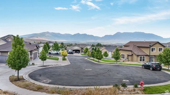 View of asphalt road featuring a residential view, a mountain view, curbs, and sidewalks | Image 13