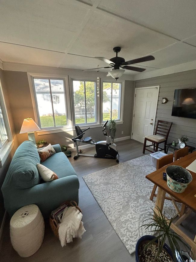 Living room with ceiling fan, wood walls, and wood finished floors | Image 13
