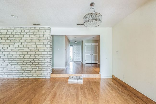 Unfurnished dining area with wood finished floors, a chandelier, visible vents, and baseboards | Image 9
