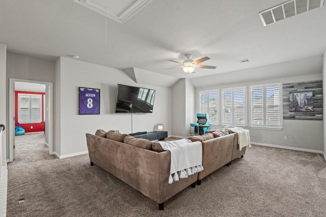 Carpeted living area with attic access, ceiling fan, and baseboards | Image 24