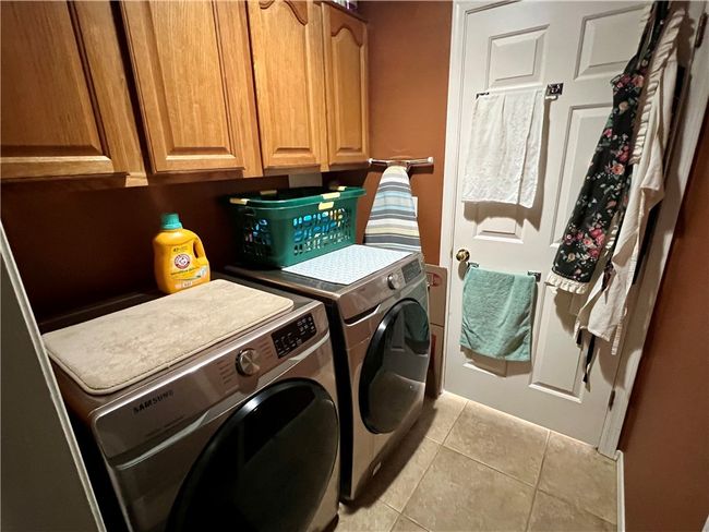 Laundry room featuring washing machine and clothes dryer, cabinet space, and light tile patterned floors | Image 33