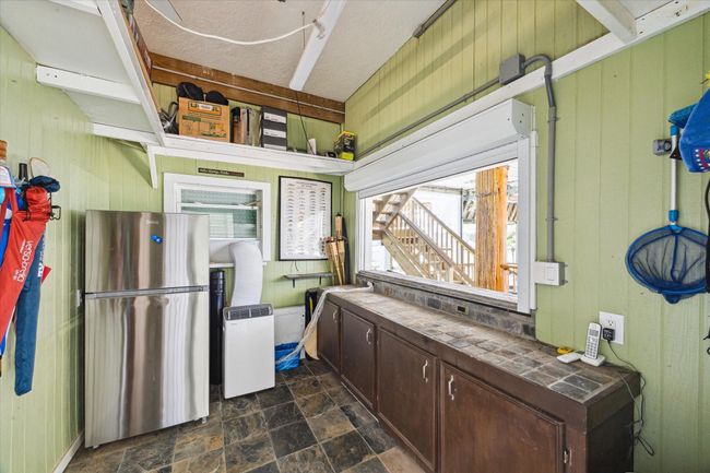 Experience outdoor dining with ease in this air-conditioned tiki bar, featuring an electric storm shutter window for seamless entertaining. | Image 26