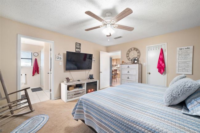 Carpeted bedroom featuring ceiling fan, ensuite bath, and a textured ceiling | Image 10