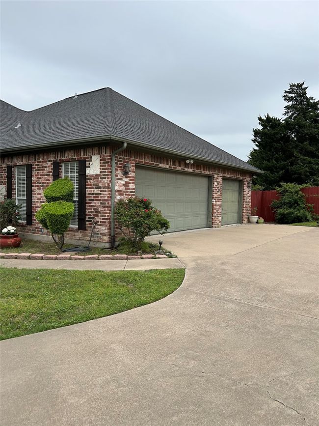 View of side of home with a garage, brick siding, and roof with shingles | Image 22