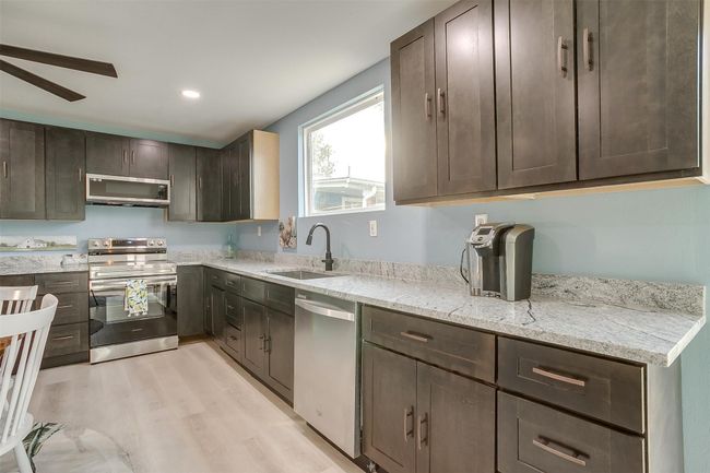 Kitchen with a ceiling fan, a sink, dark brown cabinetry, light wood-style flooring, and appliances with stainless steel finishes | Image 20