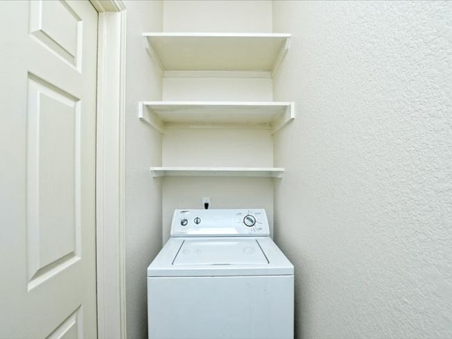 Washroom featuring washer / clothes dryer, a textured wall, and laundry area | Image 10