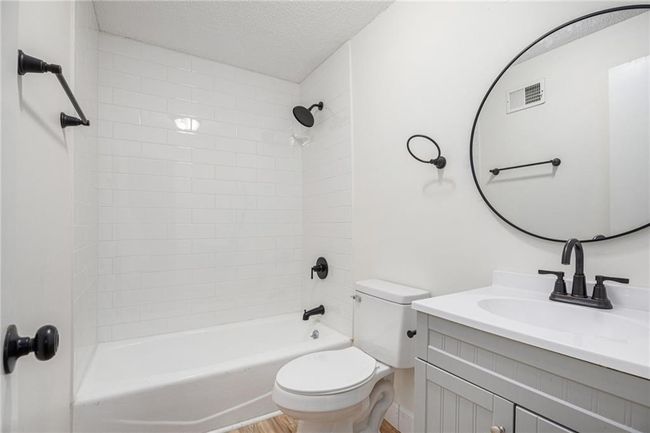 Bathroom with toilet, vanity, washtub / shower combination, and a textured ceiling | Image 18