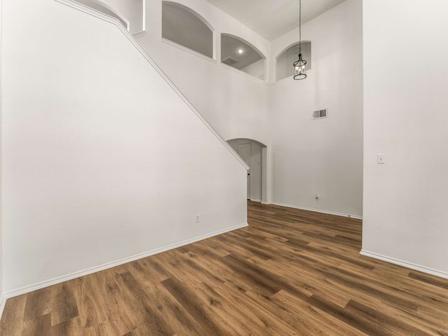 Unfurnished room with arched walkways, dark wood finished floors, and a towering ceiling | Image 8
