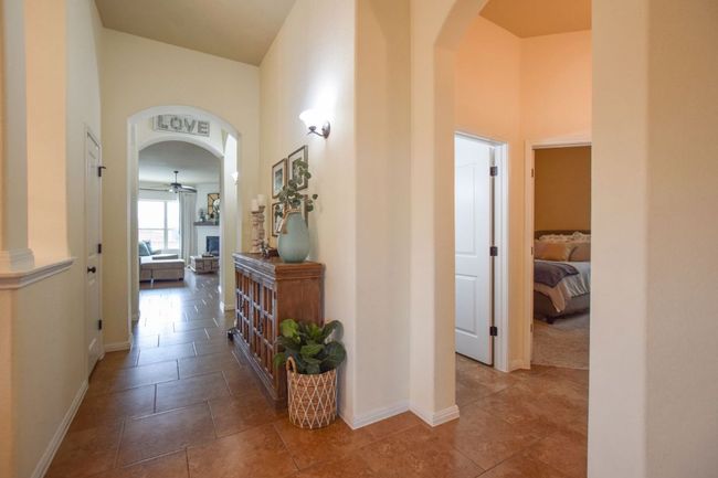Corridor featuring a high ceiling, tile patterned floors, arched walkways, and baseboards | Image 12