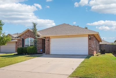 Ranch-style house with a front yard and a garage | Image 1