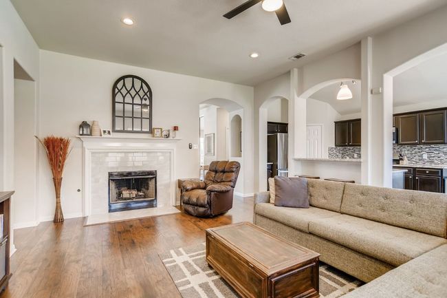 Living room featuring ceiling fan, arched walkways, wood finished floors, a fireplace, and recessed lighting | Image 15