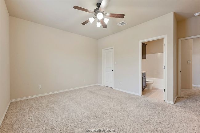 Unfurnished bedroom with ensuite bathroom, baseboards, visible vents, light colored carpet, and a ceiling fan | Image 18