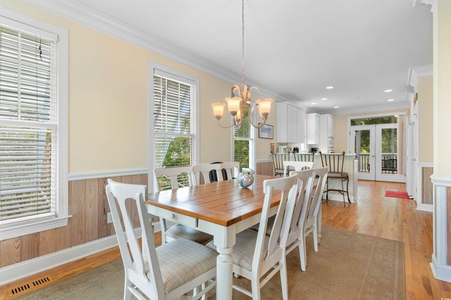 Dining room with plenty of natural light, crown molding, a chandelier, a wainscoted wall, and light wood-style flooring | Image 10