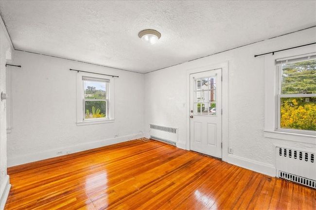 Empty room featuring wood-type flooring, a wealth of natural light, and radiator | Image 18