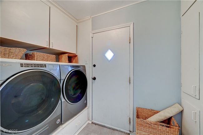 Clothes washing area with cabinet space, washer and dryer, and crown molding | Image 59