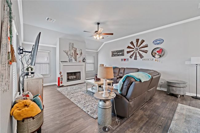 Living room with a ceiling fan, wood finished floors, crown molding, and visible vents | Image 18