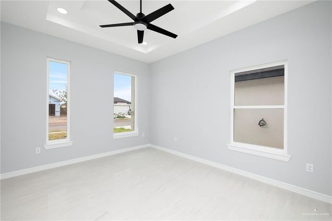 Empty room featuring a raised ceiling, ceiling fan, recessed lighting, and baseboards | Image 11