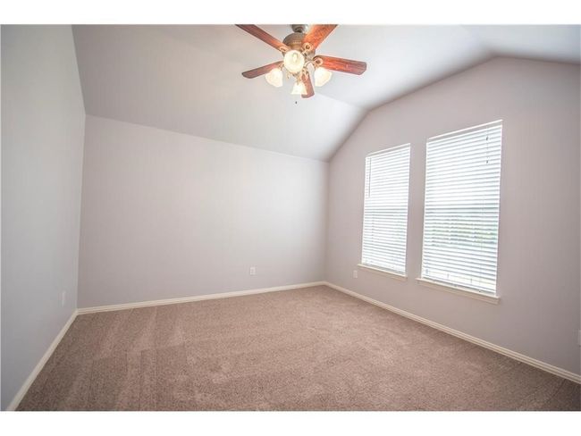 Carpeted spare room featuring lofted ceiling, ceiling fan, and baseboards | Image 18