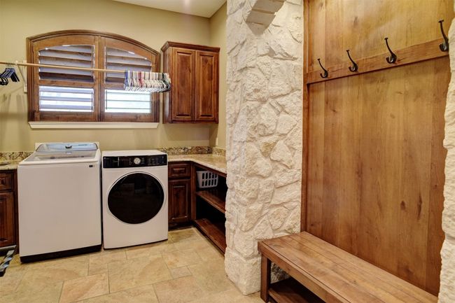 Downstairs main utility room has room for a large stand up freezer or extra refrigerator, built in hall tree, counter space for laundry folding and extra storage shelves and cabinets. | Image 35