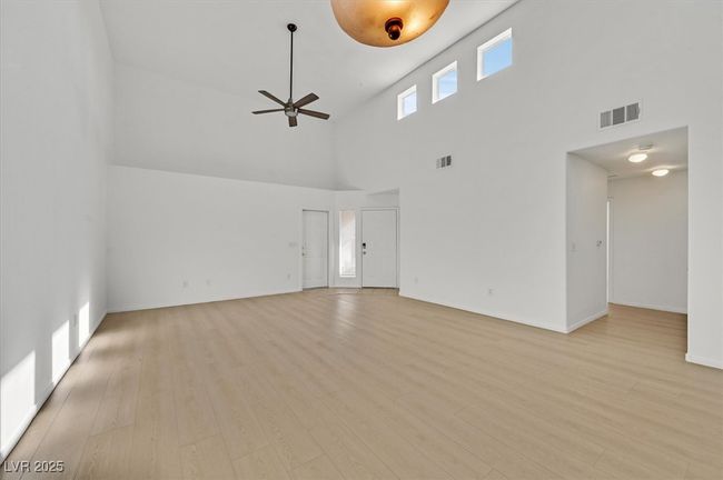 Unfurnished living room featuring high vaulted ceiling, ceiling fan, and light wood finished floors | Image 4