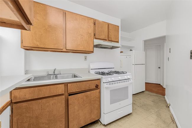 Kitchen featuring under cabinet range hood, white appliances, light countertops, and open shelves | Image 16